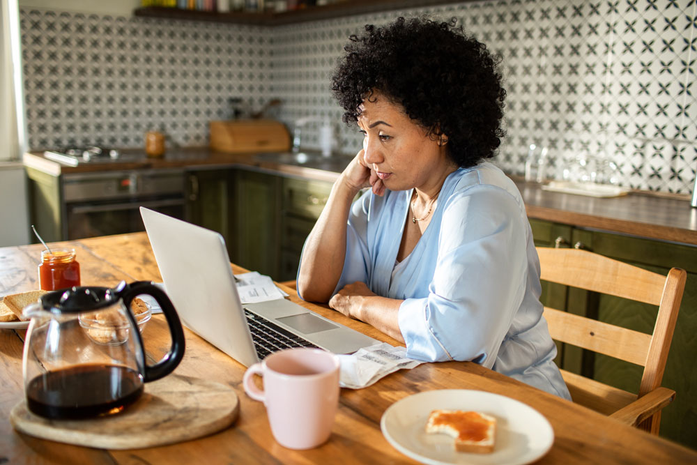 Woman at kitchen table looking at computer